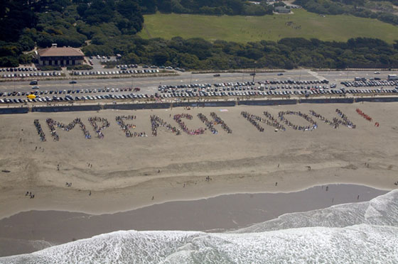 hundreds gather on beach in san francisco to spell out Impeach now.